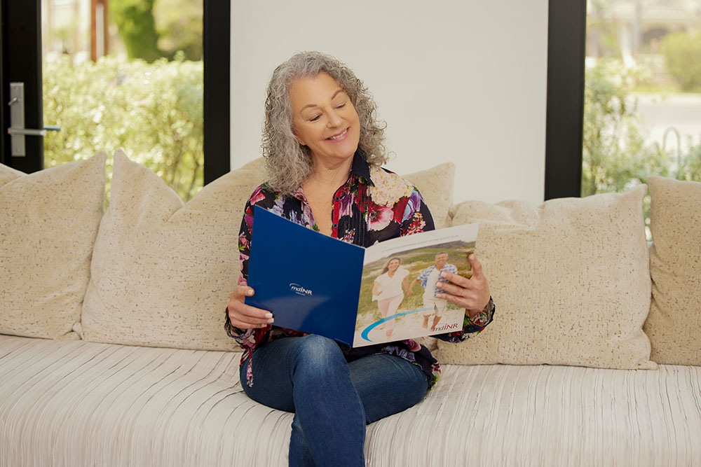 patient sitting on the couch reading INR booklet